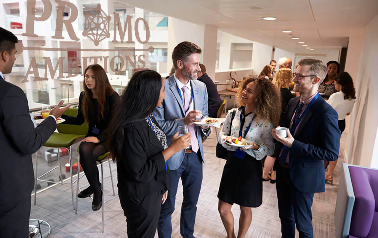  A group of people networking at a business event, talking and laughing while holding drinks and plates of food.